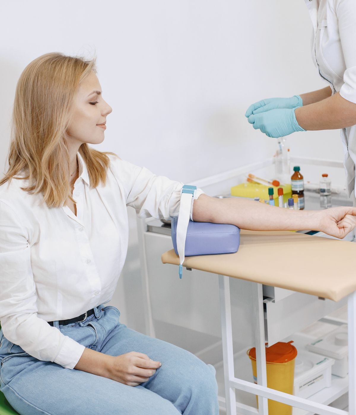 Phlebotomist preparing to collect a blood sample from a seated patient